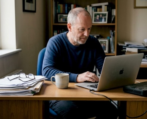 Man arbetar vid skrivbord med laptop.